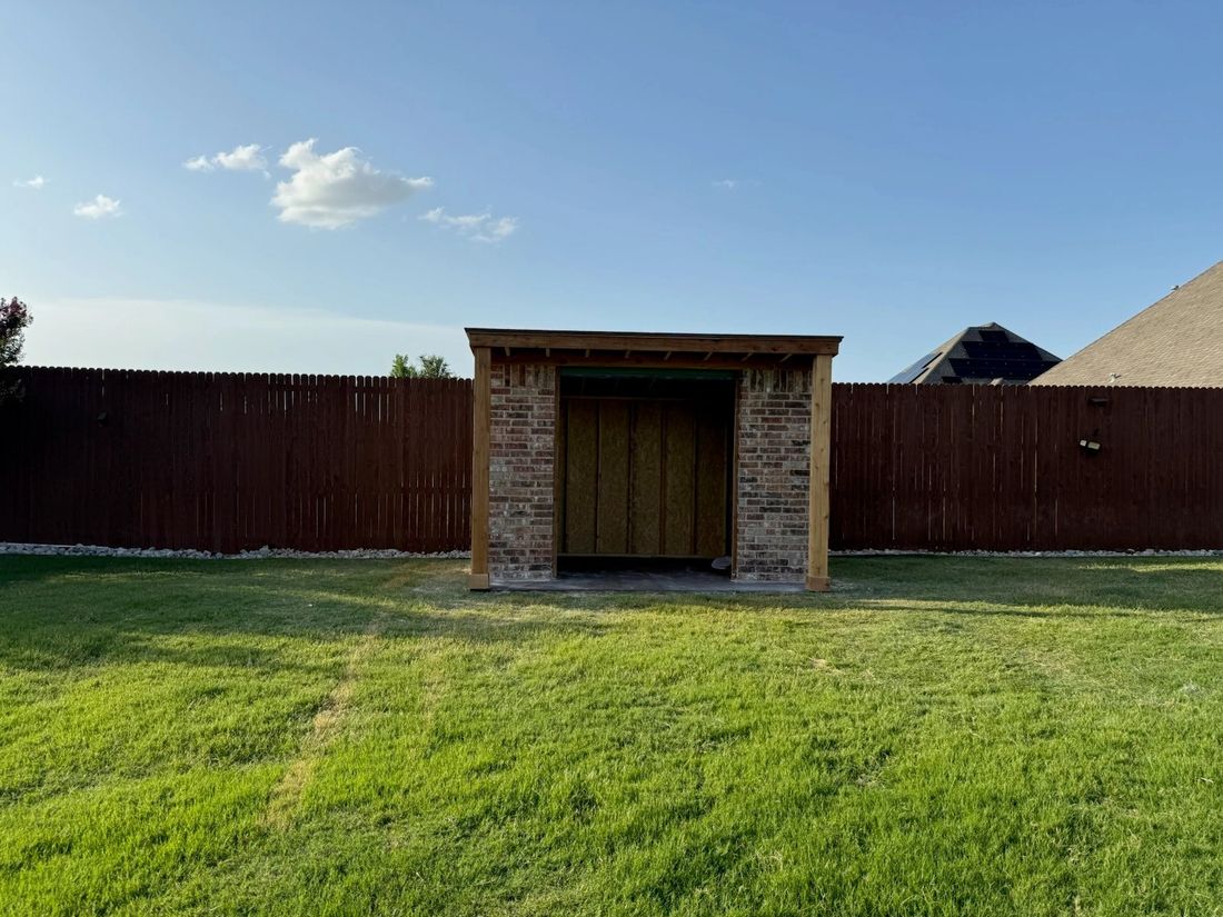 A finished brick and cedar outdoor structure with a pergola-style roof overhang, daytime