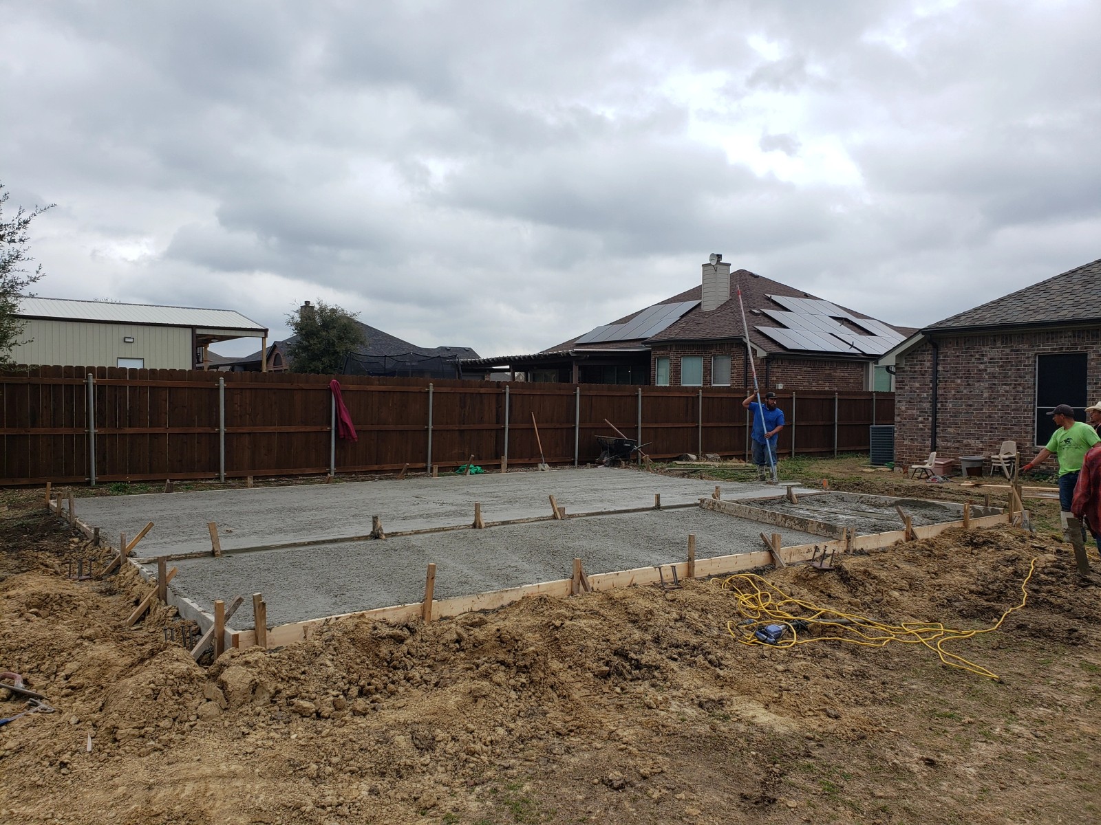 Fresh concrete slab foundation being poured in a backyard