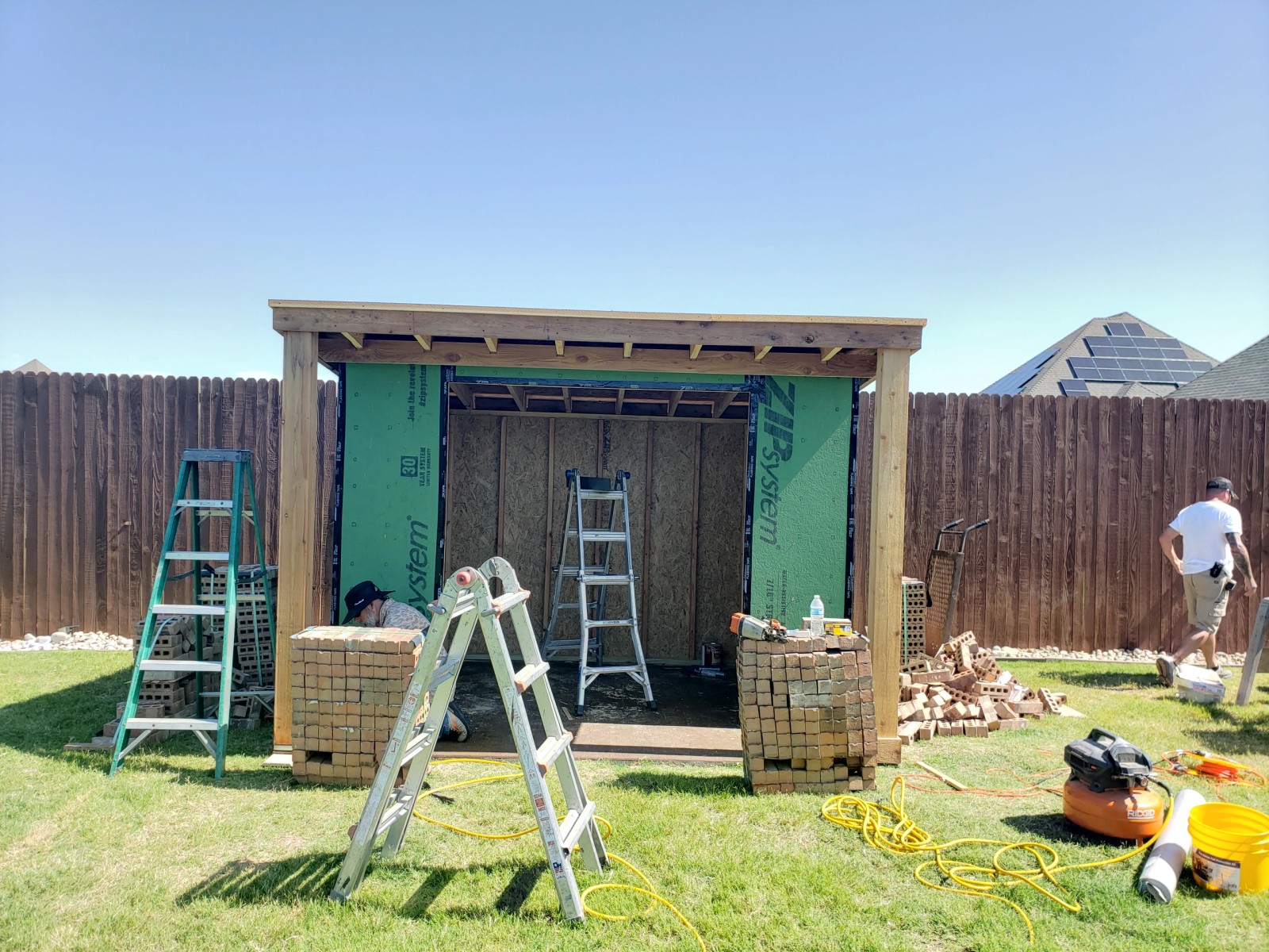 Framed structure with house-wrap sheathing and brick coursing starting at the base