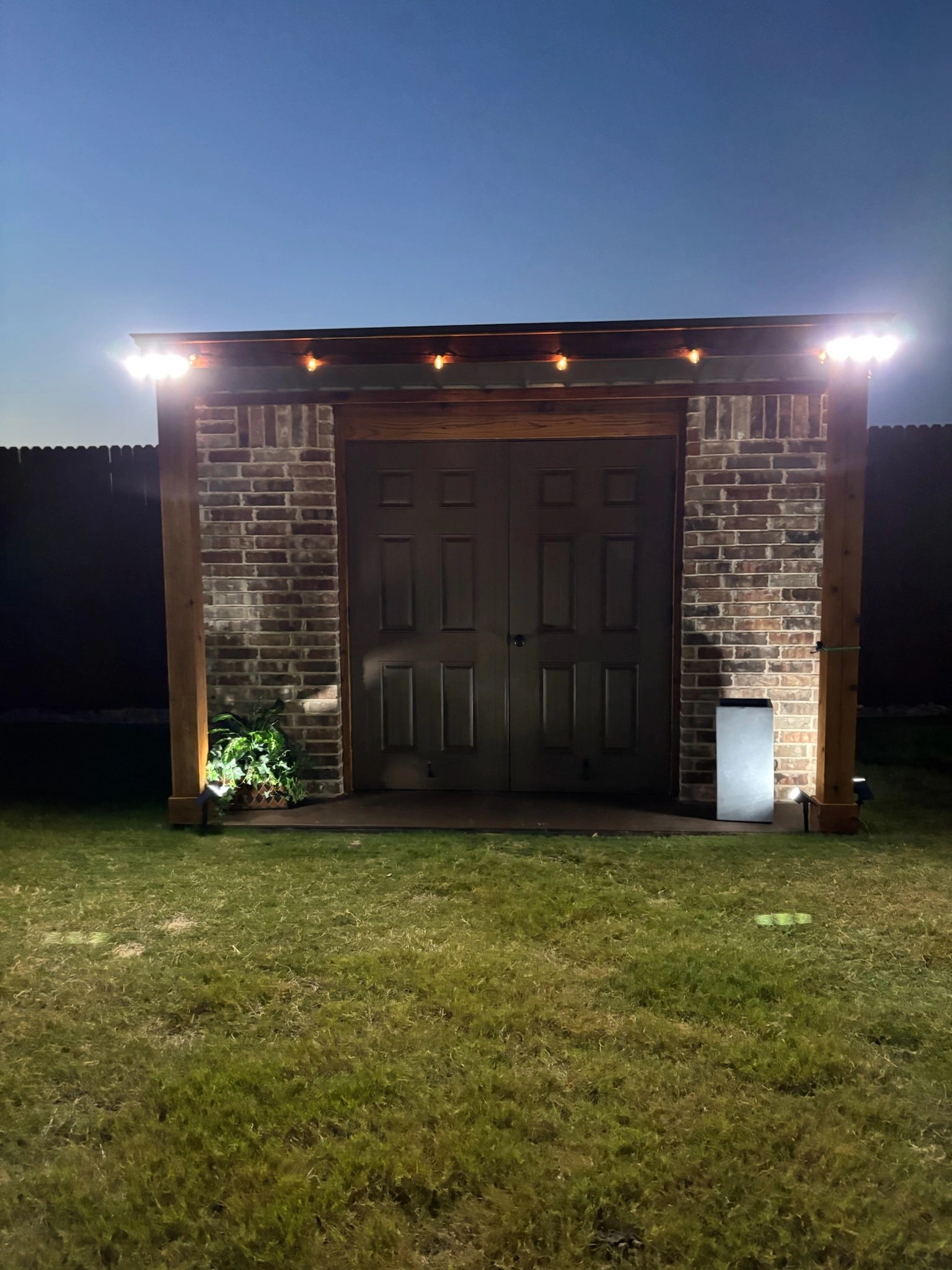 Finished brick storage building lit up in the evening with string lights