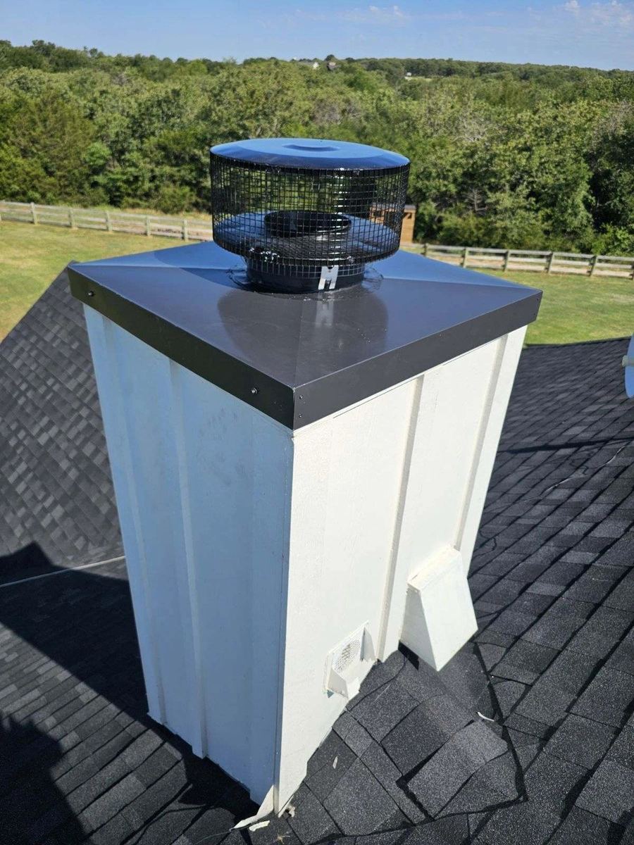 Close-up of a finished chimney cap and flashing on an asphalt shingle roof