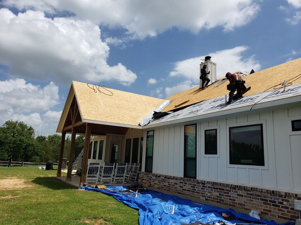 Roof decking installed with a dramatic blue sky and clouds, chimney flashing in progress